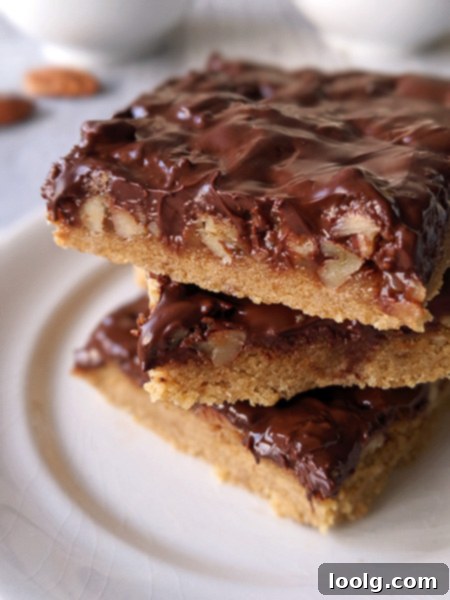 Closeup of the gooey caramel and pecan layer underneath the chocolate on a freshly baked Turtle Cookie Bar.