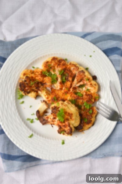 Beautifully plated Cajun Roasted Cauliflower Steak garnished with fresh herbs, showcasing its appealing golden-brown crust.