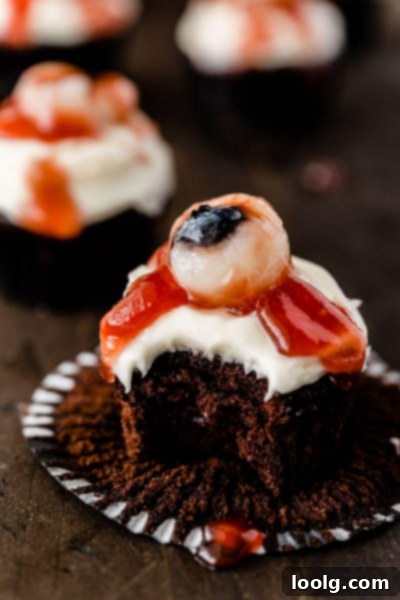 Ghoulish Gaze Cupcakes 6 A close-up of a single Eyeball Halloween Cupcake with chocolate base, cream cheese frosting, lychee eye, and jam blood.