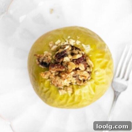 Quick & Easy Air Fryer Baked Apples 6 top view photo of an air fryer baked apple with an oat-based crumble filling with a fork set to the side on a plate