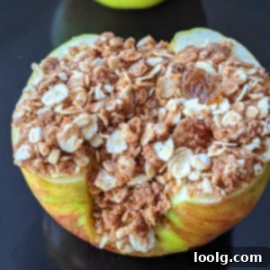 Quick & Easy Air Fryer Baked Apples 7 closeup photo showing an air fryer baked apple with an oat-based crumble filling with cinnamon, raisins and pecans