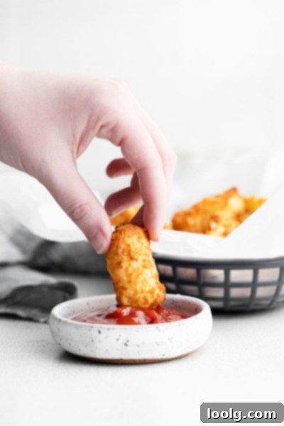 Crispy Air Fryer Tater Tots with Hash Brown Hack 5 hand dipping tater tot in ketchup