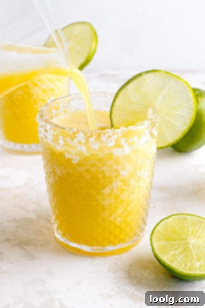 Easy 4-Ingredient Frozen Pineapple Margarita 2 pineapple margarita being poured into glass