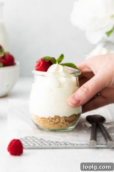 Creamy Cheesecake Mousse 5 A hand reaching for a jar of cheesecake mousse with fresh berries on top