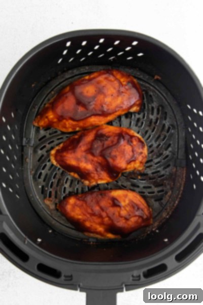 Perfect Air Fryer BBQ Chicken 6 chicken breast in air fryer basket with bbq sauce rubbed over it