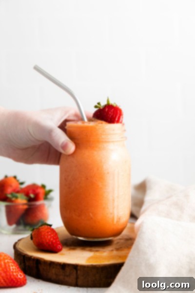 Tropical Mango Strawberry Banana Smoothie 5 hand picking up Mango Strawberry Banana Smoothie