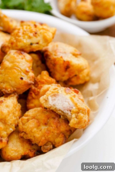 Crispy Air Fryer Popcorn Chicken 6 a piece of air fried popcorn chicken with a bite taken out, showing the crispy texture