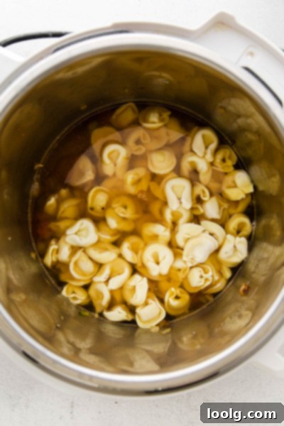 Speedy & Satisfying Tortellini Soup 5 Frozen tortellini being added to the Instant Pot with broth and vegetables