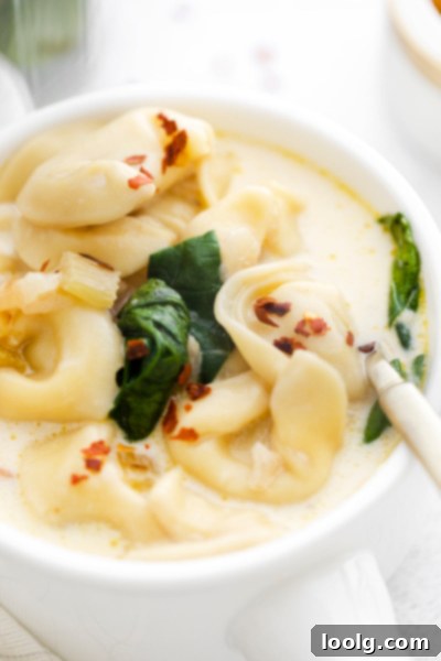 Speedy & Satisfying Tortellini Soup 9 Bowl of creamy tortellini soup garnished with red pepper flakes and fresh herbs