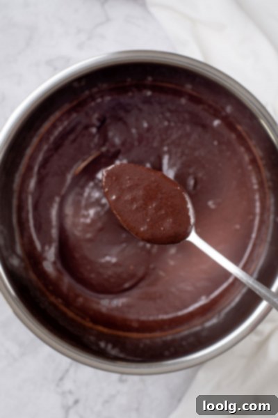 One-Pot Hot Chocolate Magic 3 A close-up shot of a glass full of Instant Pot Hot Chocolate, showcasing its rich, dark brown color and creamy texture. It's topped with whipped cream and a light dusting of cocoa powder.