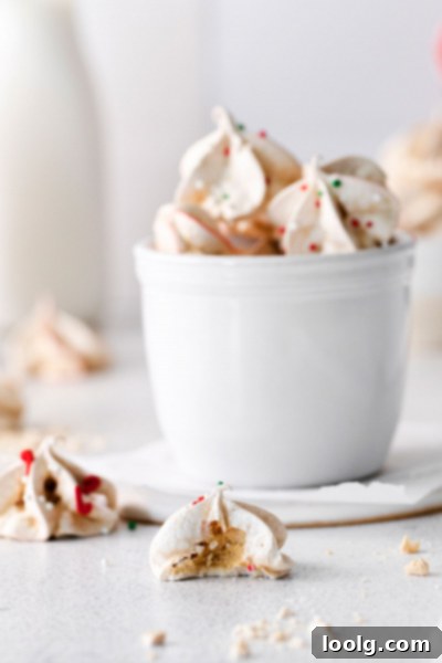Frost Kissed Mint Puffs 8 A festive array of red and white peppermint meringues with sprinkles, arranged in a visually appealing pattern.