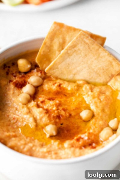 Smoky Red Pepper Hummus 2 Roasted Red Pepper Hummus close up in a white bowl with crackers and raw vegetables