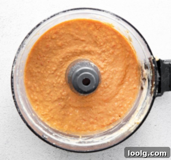 Smoky Red Pepper Hummus 4 A bowl of roasted red pepper hummus with various fresh vegetables and crackers arranged around it.