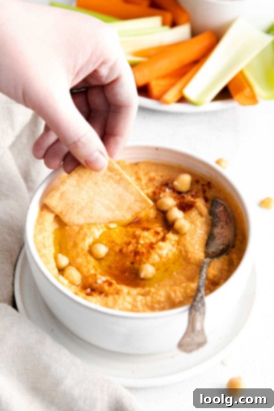 Smoky Red Pepper Hummus 7 Several small bowls of roasted red pepper hummus on a wooden board