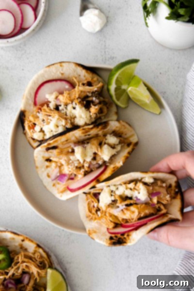 Effortless Instant Pot Shredded Chicken Tacos 9 A bowl of shredded chicken next to an Instant Pot and various taco ingredients.