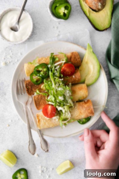 Air-Fried Taquito Perfection 2 Air Fryer Taquitos on a white plate with sour cream and guacamole