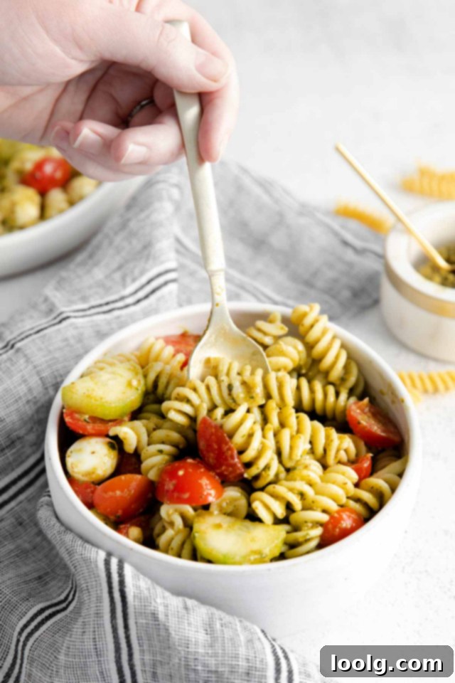 Refreshing Summer Pesto Pasta Salad 4 spoon digging into bowl of pasta salad