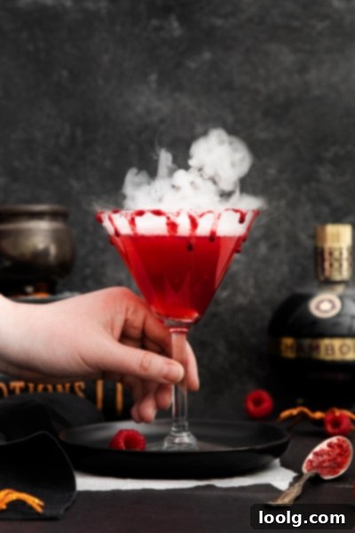 Crimson Kiss 8 A stunning final shot of the Vampire's Kiss Cocktail, beautifully presented in a martini glass with a blood-red rim and dramatic dry ice fog. Perfect for a memorable Halloween celebration.