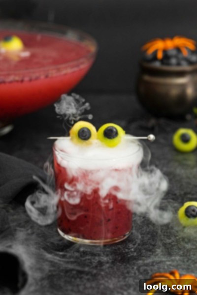 Fright Night Fizz 7 A glass of non-alcoholic Halloween punch with melon eyeballs and a smoky effect, alongside a dry ice container.