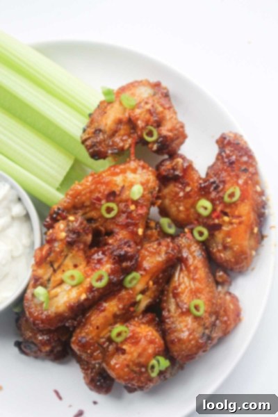 Baked or Air Fried Honey Garlic Wings 2 Plate of golden-brown honey garlic chicken wings, garnished with chopped green onions, ready to be served