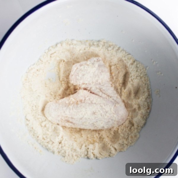 Baked or Air Fried Honey Garlic Wings 4 Raw chicken wings coated in flour and spices, ready for air frying or baking, in a mixing bowl