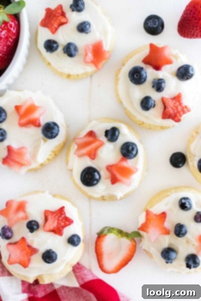Patriotic Cookies for Memorial Day and July Fourth 2 image of Memorial Day cookies using basic sugar cookie ingredients topped with a cream cheese frosting and strawberry star cut-outs with fresh blueberries giving it a red, white and blue theme scattered on a white background.