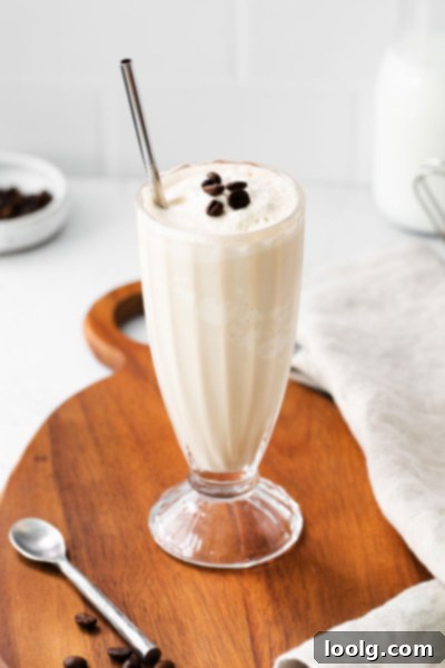 Velvet Mocha Shake 2 Creamy mocha milkshake in a tall glass, garnished with chocolate-covered espresso beans and a silver straw.