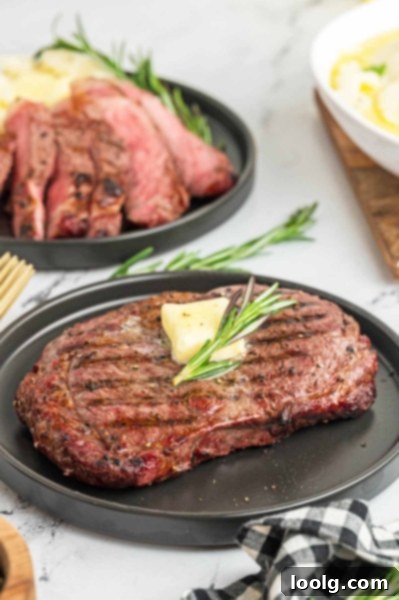 Ultimate Smoked Ribeye 2 A perfectly smoked ribeye steak with a deep red interior and a smoky crust, sliced and ready to serve on a cutting board.