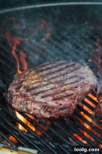 Ultimate Smoked Ribeye 7 A close-up shot of a smoked ribeye steak on a smoker grate, with perfect grill marks forming during the searing phase.