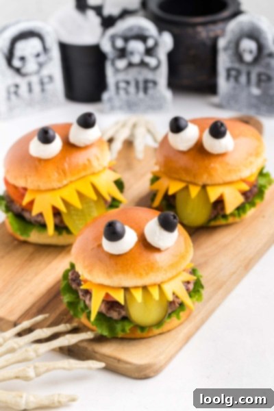 The Ultimate Monster Burger 2 Two monster burgers for Halloween, decorated with cheese teeth, pickle tongues, and olive-mozzarella eyes.