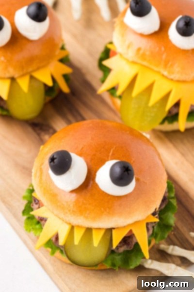 The Ultimate Monster Burger 3 A close-up of a finished Halloween monster burger showing the pickle tongue, cheese teeth, and olive-mozzarella eyes.