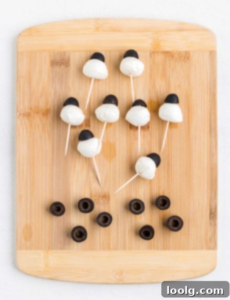 The Ultimate Monster Burger 7 Step-by-step image showing how to assemble the monster eyes using mozzarella balls, black olives, and toothpicks.