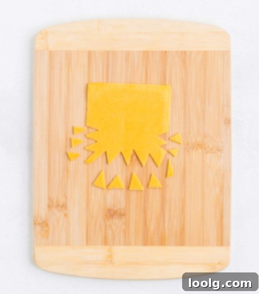 The Ultimate Monster Burger 8 A hand cutting cheese slices into triangles to create monster teeth for Halloween burgers.