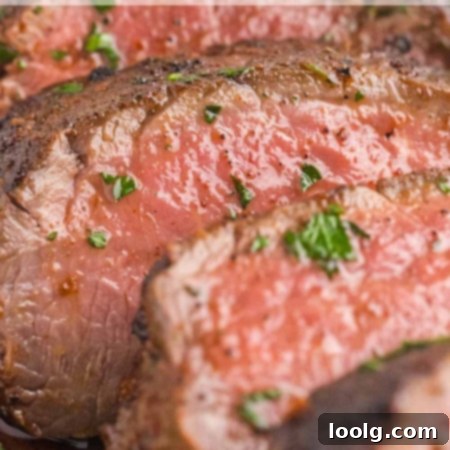 Prime Venison Loin 9 A perfectly seared and sliced venison backstrap, drizzled with garlic herb butter, with a fresh parsley garnish.