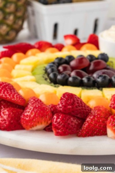 Kaleidoscope of Fruit 4 A close-up of hands carefully arranging fruit chunks on a platter to form the rainbow, showcasing the preparation process.