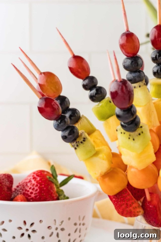 Rainbow Fruit Pops 6 Close-up of the prepared fruit, including strawberries, goldenberries, pineapple, kiwi, blueberries, and grapes, ready for skewering.