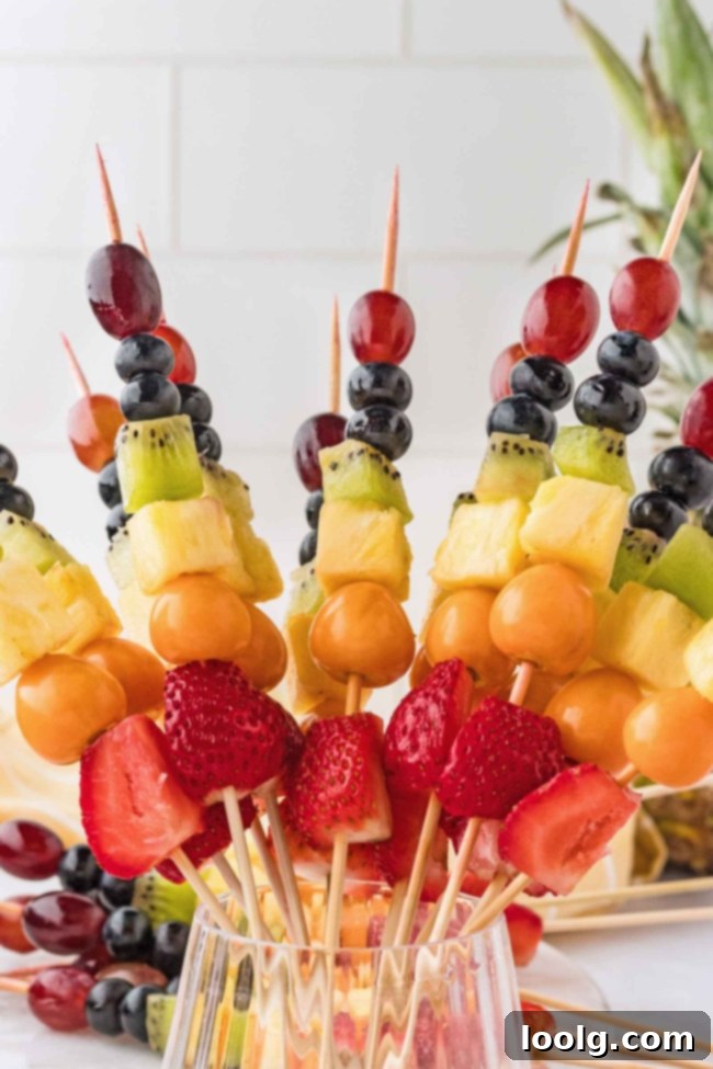 Rainbow Fruit Pops 7 A large, impressive display of rainbow fruit skewers arranged in a full circle, creating a vibrant edible rainbow centerpiece.