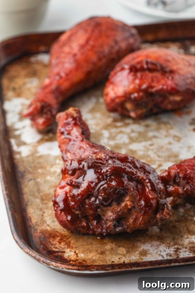 Smoked Turkey Drumsticks 6 A perfectly smoked turkey leg, glistening with barbecue sauce, being removed from the smoker, showcasing its rich color and tender appearance.