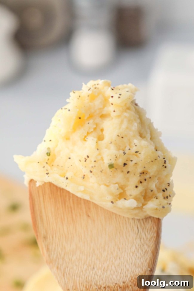 Creamy Cheesy Mashed Potatoes 3 A close-up shot of a fork scooping a generous portion of cheesy mashed potatoes, showing their creamy texture and golden color, next to a piece of smoked turkey.
