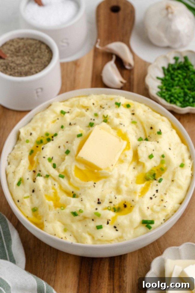 Golden Velvety Yukon Gold Mash 2 A bowl of creamy Yukon Gold mashed potatoes ready to be served, with a pat of melting butter and fresh herbs.