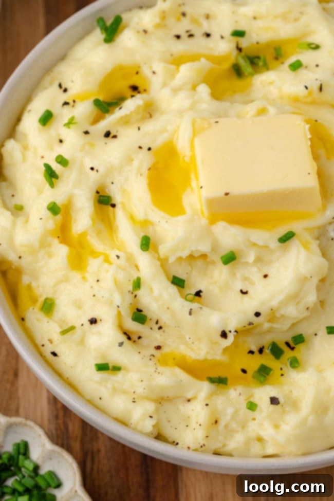 Golden Velvety Yukon Gold Mash 7 A large serving bowl filled with creamy mashed potatoes, garnished with fresh herbs, and ready to be served.