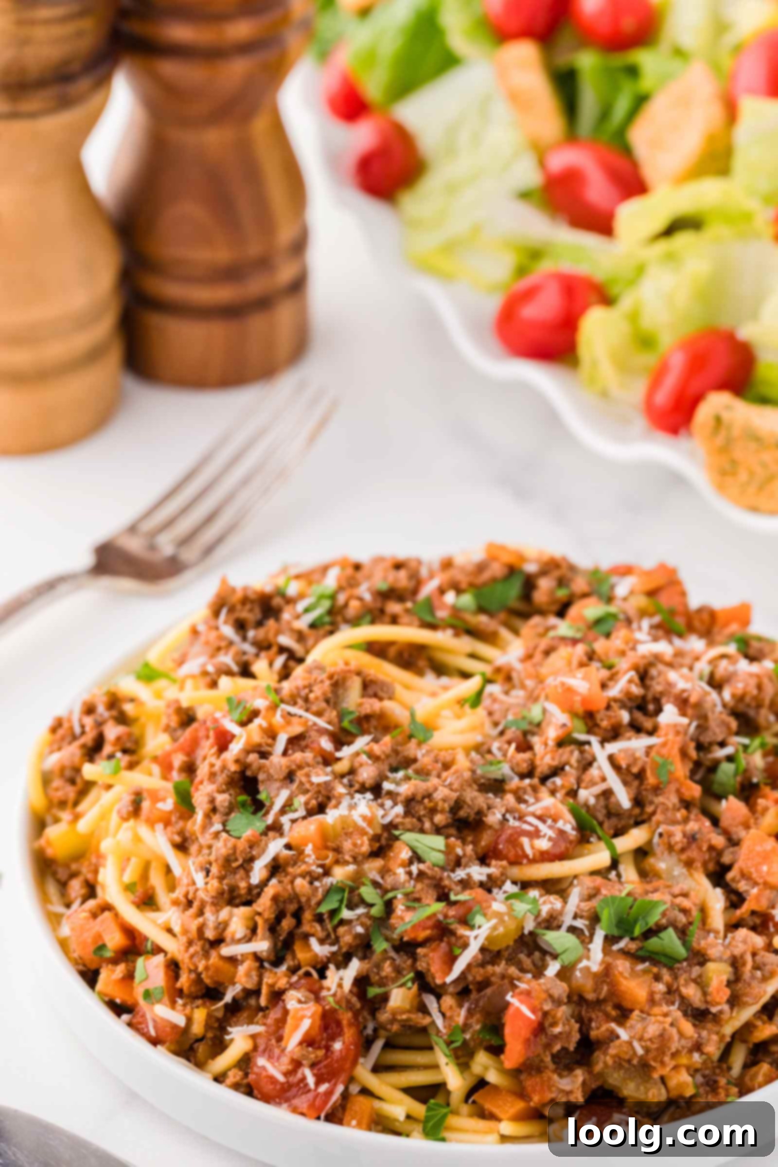 Slow-Simmered Venison Bolognese 13 plate of bolognese on a white table with a salad in the background