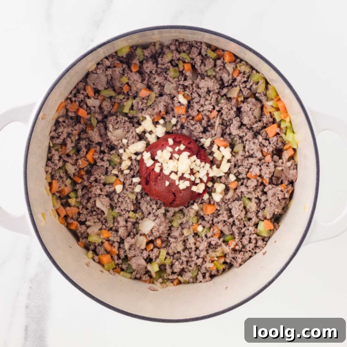 Slow-Simmered Venison Bolognese 7 adding garlic and tomato paste to pot of venison bolognese
