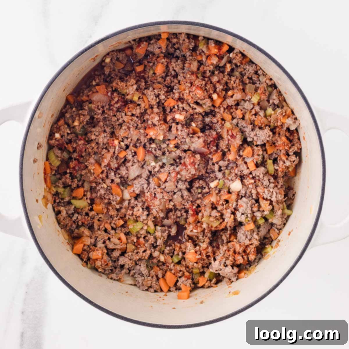 Slow-Simmered Venison Bolognese 8 ground venison being cooked in white dutch oven