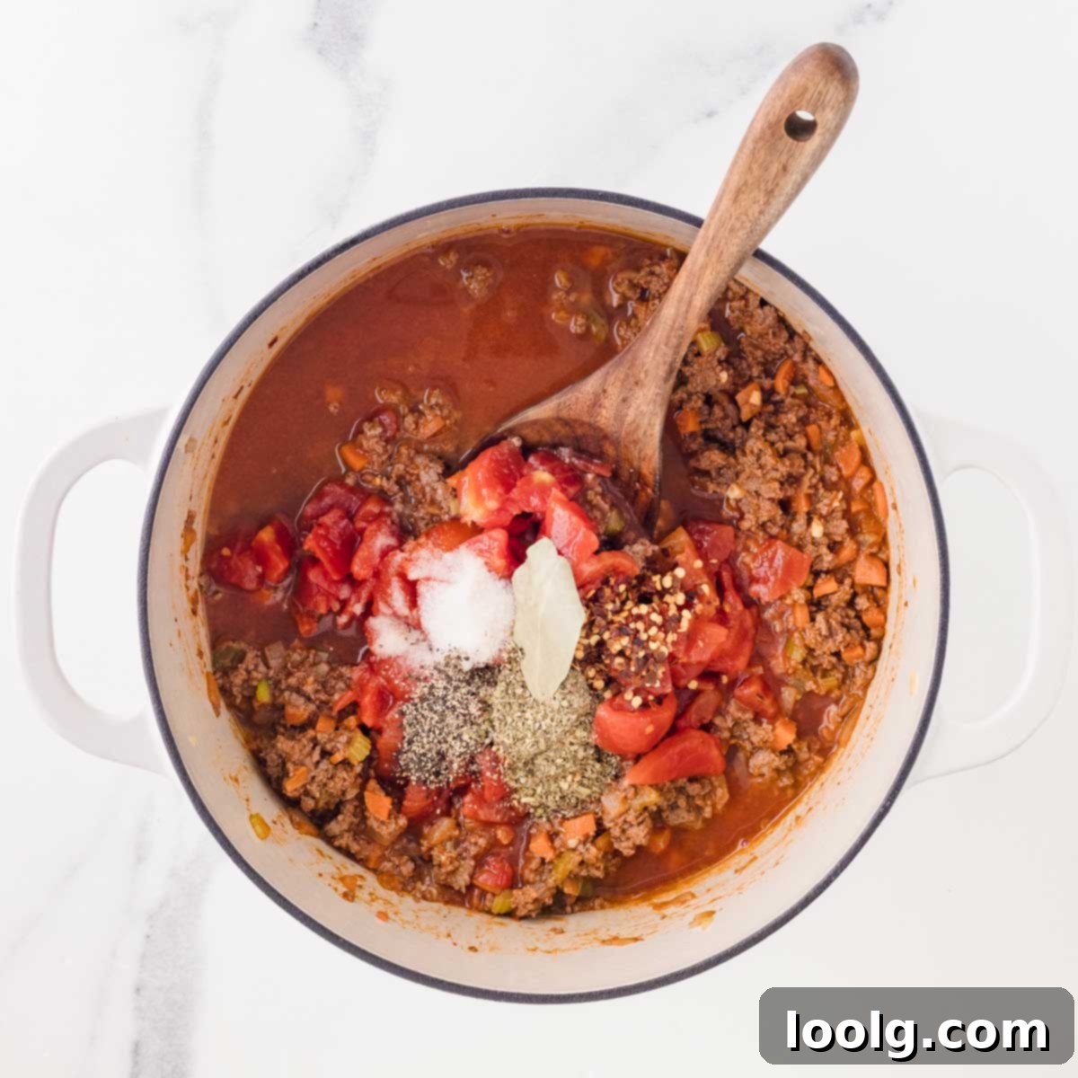 Slow-Simmered Venison Bolognese 10 adding in diced tomatoes, broth, bay leaf, and seasonings to pot of bolognese