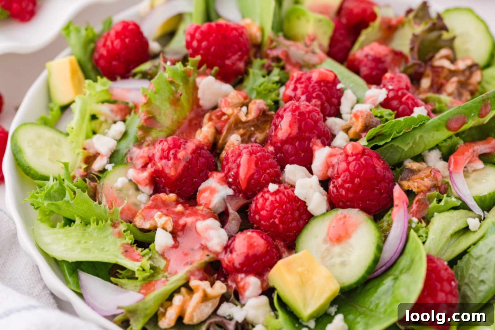 Refreshing Raspberry Salad 5 raspberry salad on a white plate, mixed up with raspberry vinaigrette on top