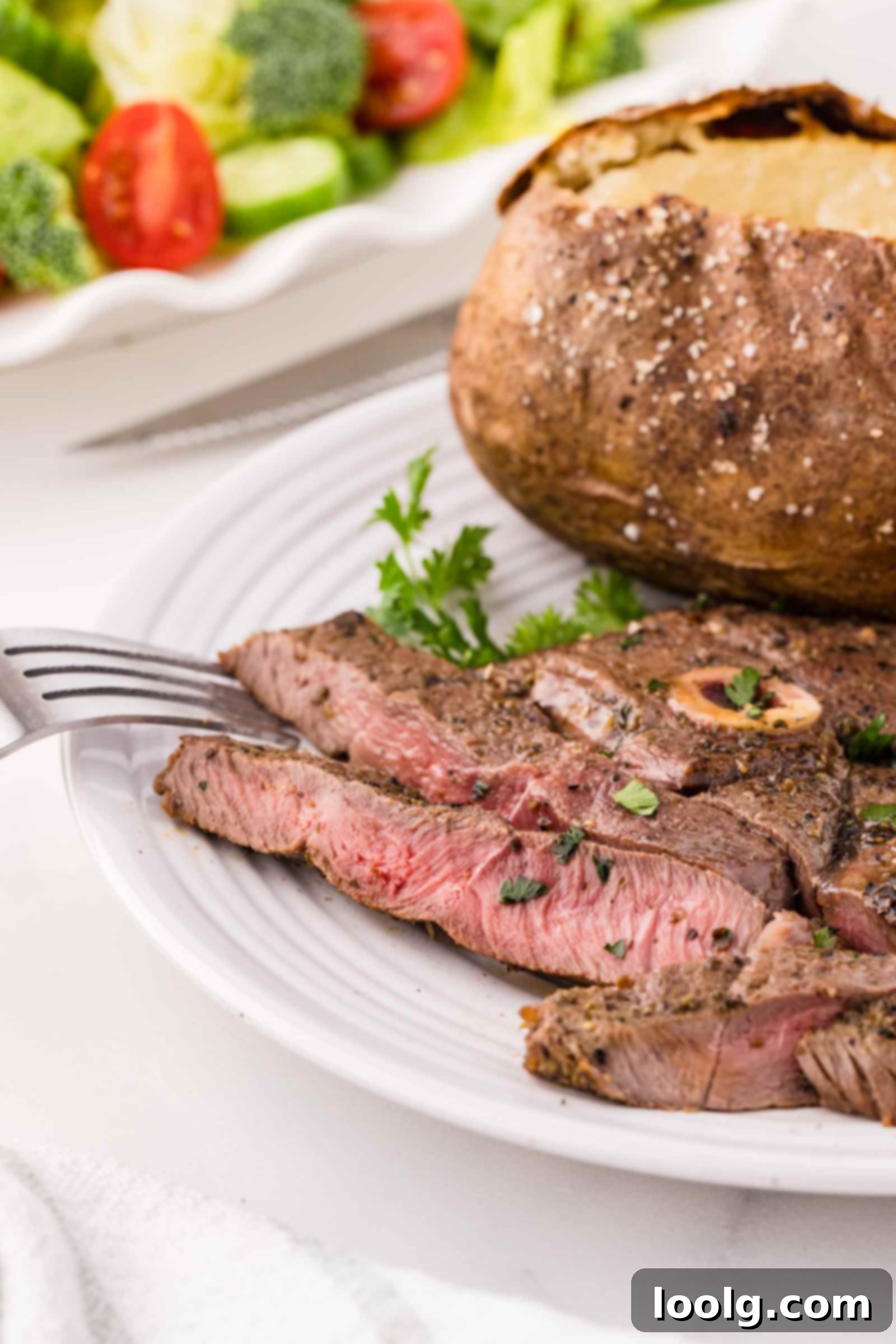 Signature Venison Steaks 6 a fork on a white plate of venison steaks