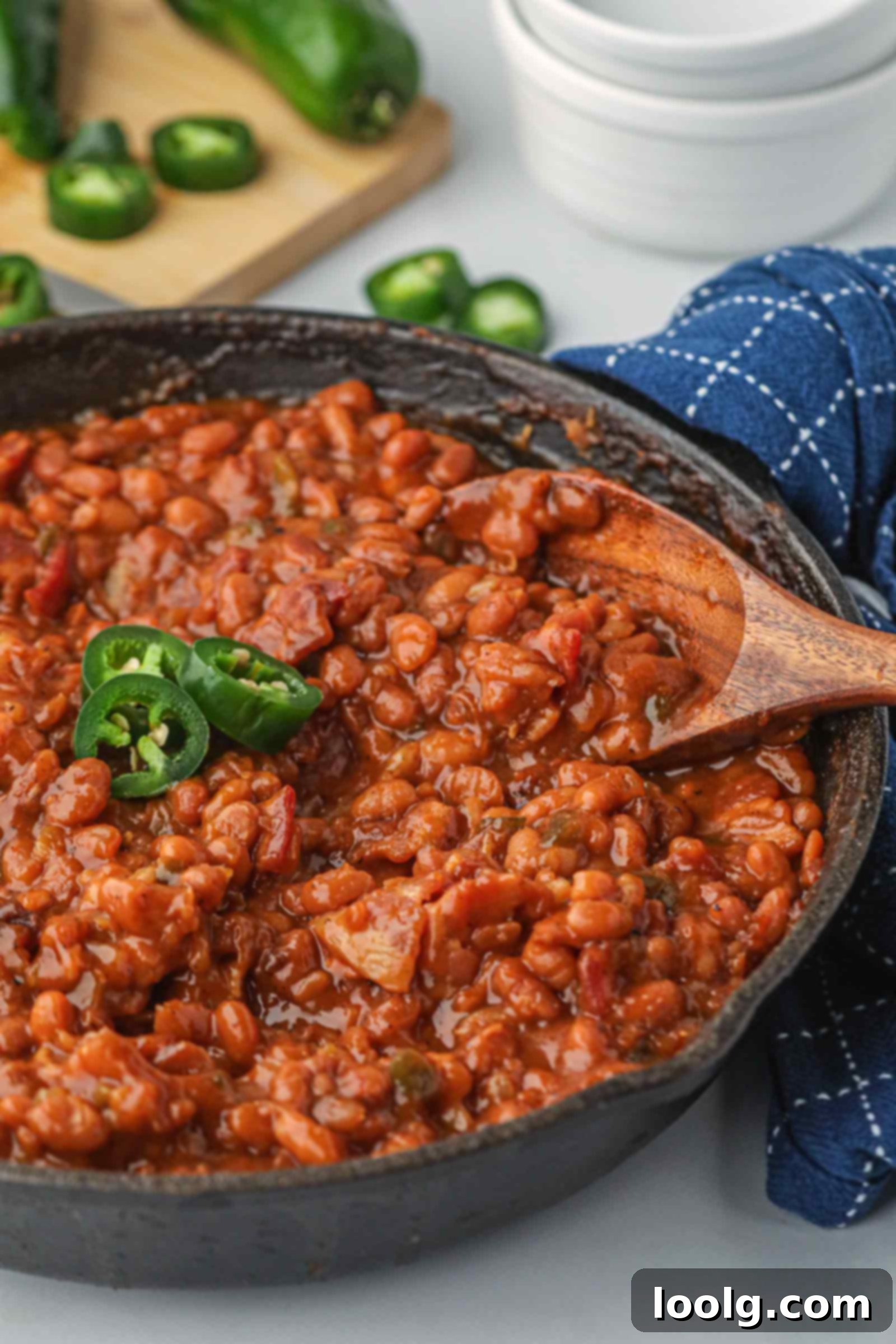 Slow-Smoked Baked Beans 2 spoon digging a cast iron skillet filled with smoked baked beans