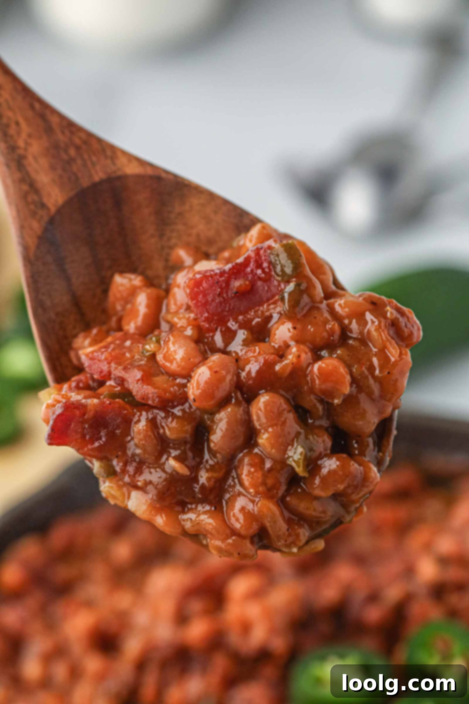 Slow-Smoked Baked Beans 7 spoon digging into cast iron skillet filled with smoked baked beans
