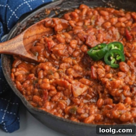 Slow-Smoked Baked Beans 9 close-up of smoked baked beans in a cast iron skillet with a bit of jalapeno on top